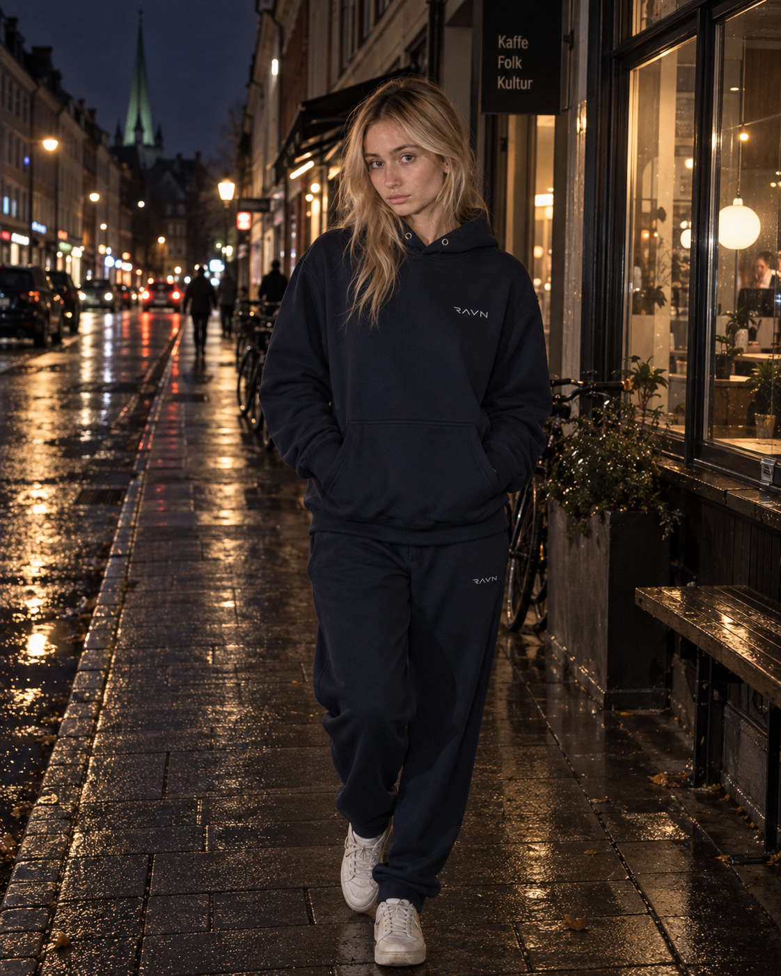 Female model wearing Ravn Nordic navy sweatwear on a wet evening street